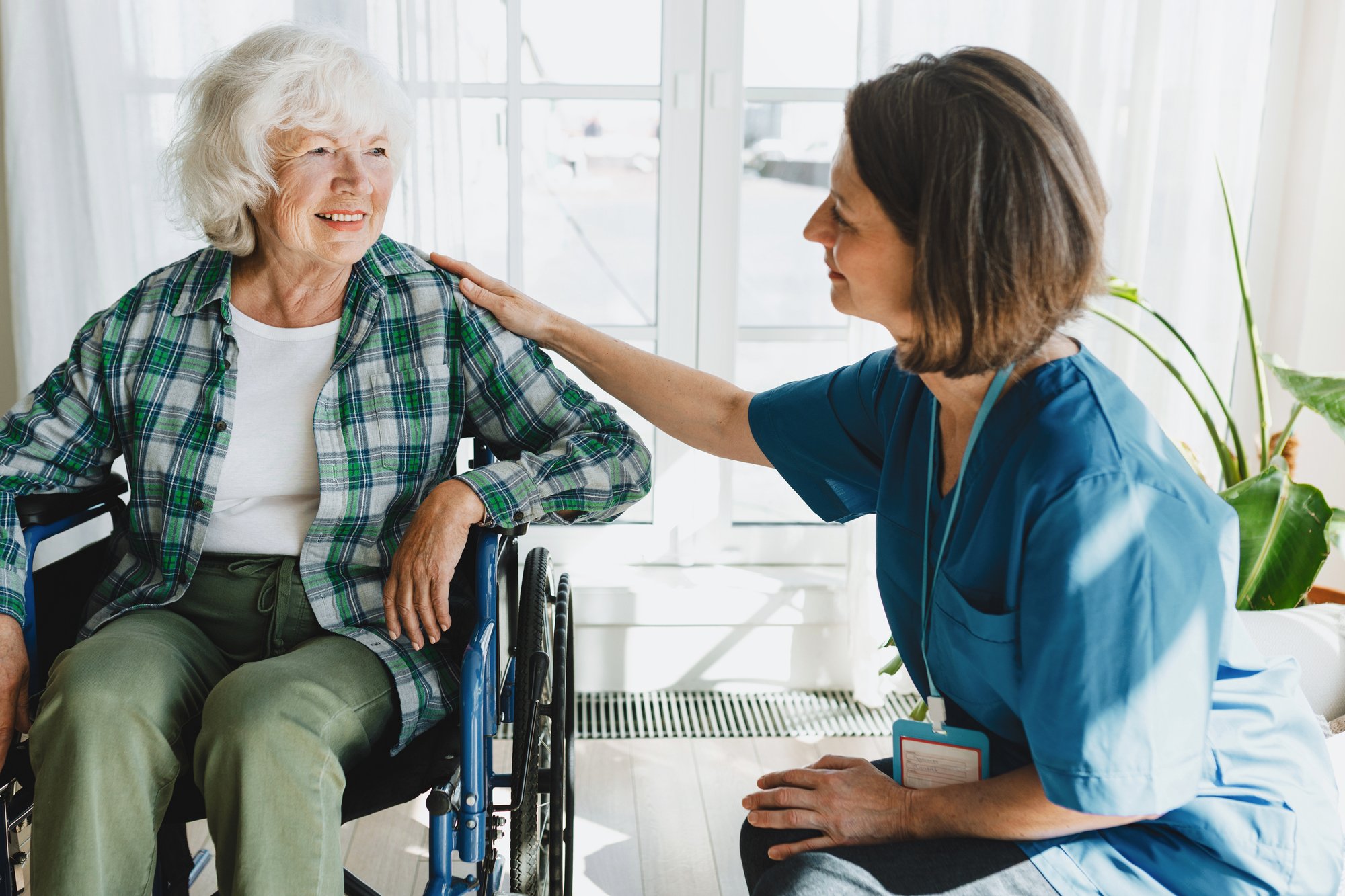 Nurse comforting an elderly patient in a wheelchair