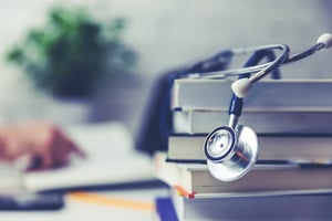 stack of textbooks with a stethoscope draped over them