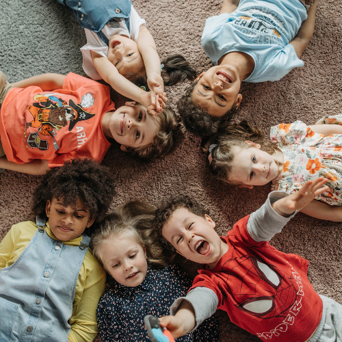 children laying in a circle with their heads teaching