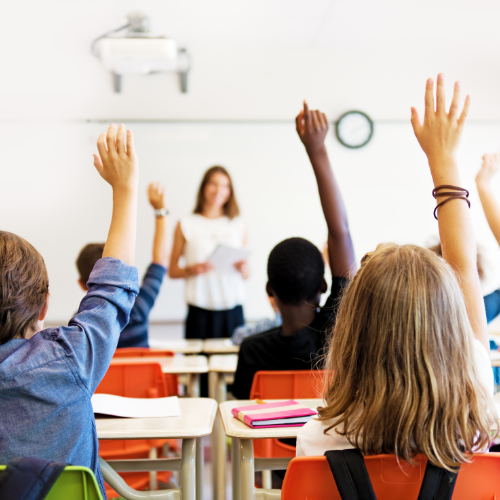 Kids raising their hands in a classroom