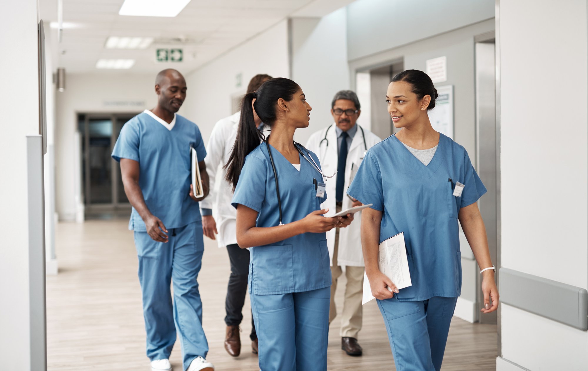 Group of five health care workers walking down a hallway
