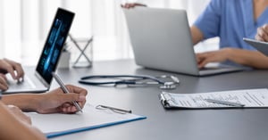 nurses sitting at a table with laptops and clipboards