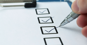 paper checklist with a person checking off boxes