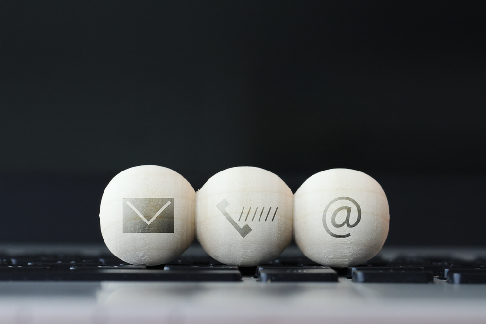 icon on wooden ball of website and internet contact us page concept on computer laptop keyboard